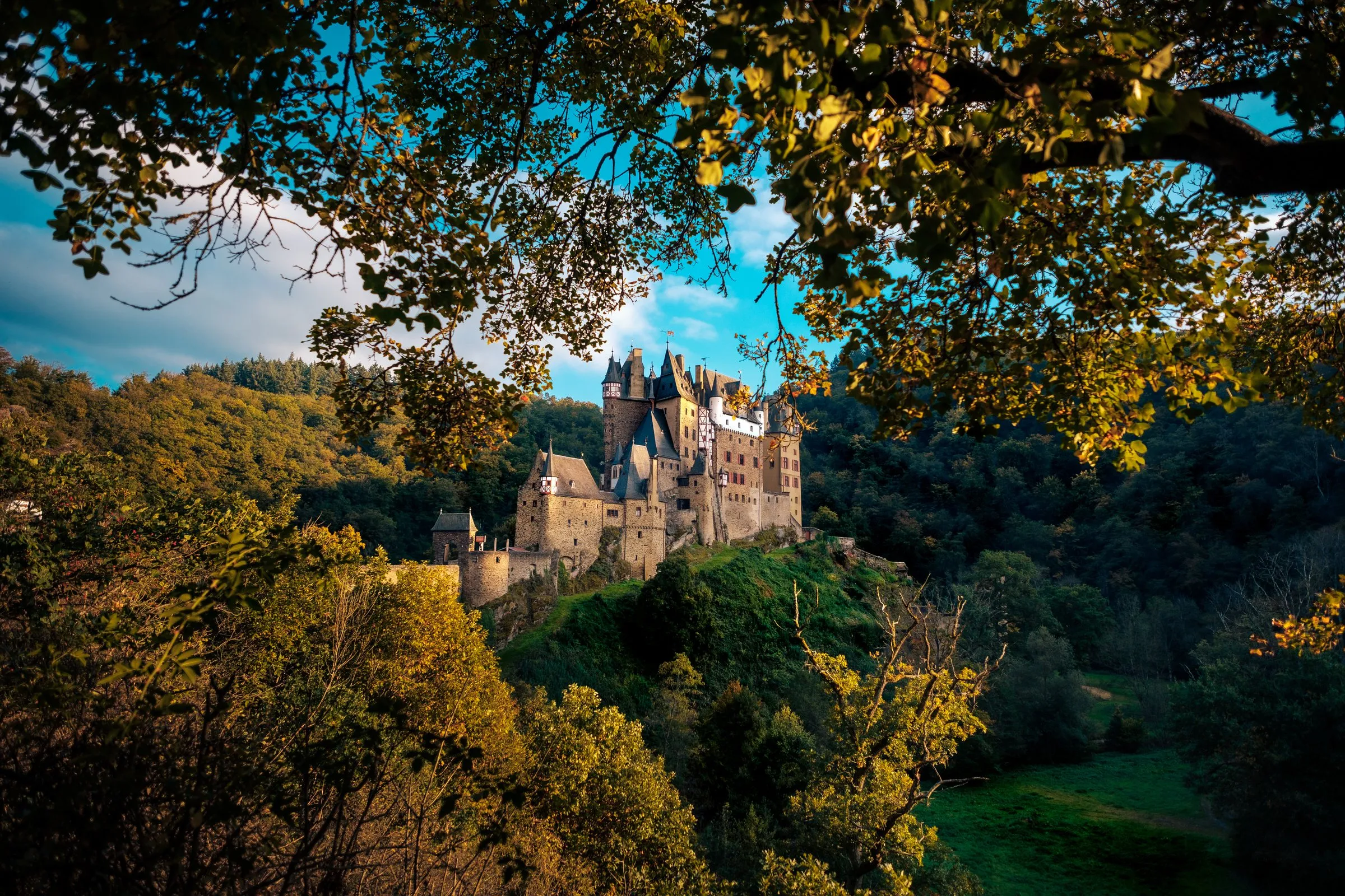 Burg Eltz im Wald, von herbstlichen Bäumen eingerahmt