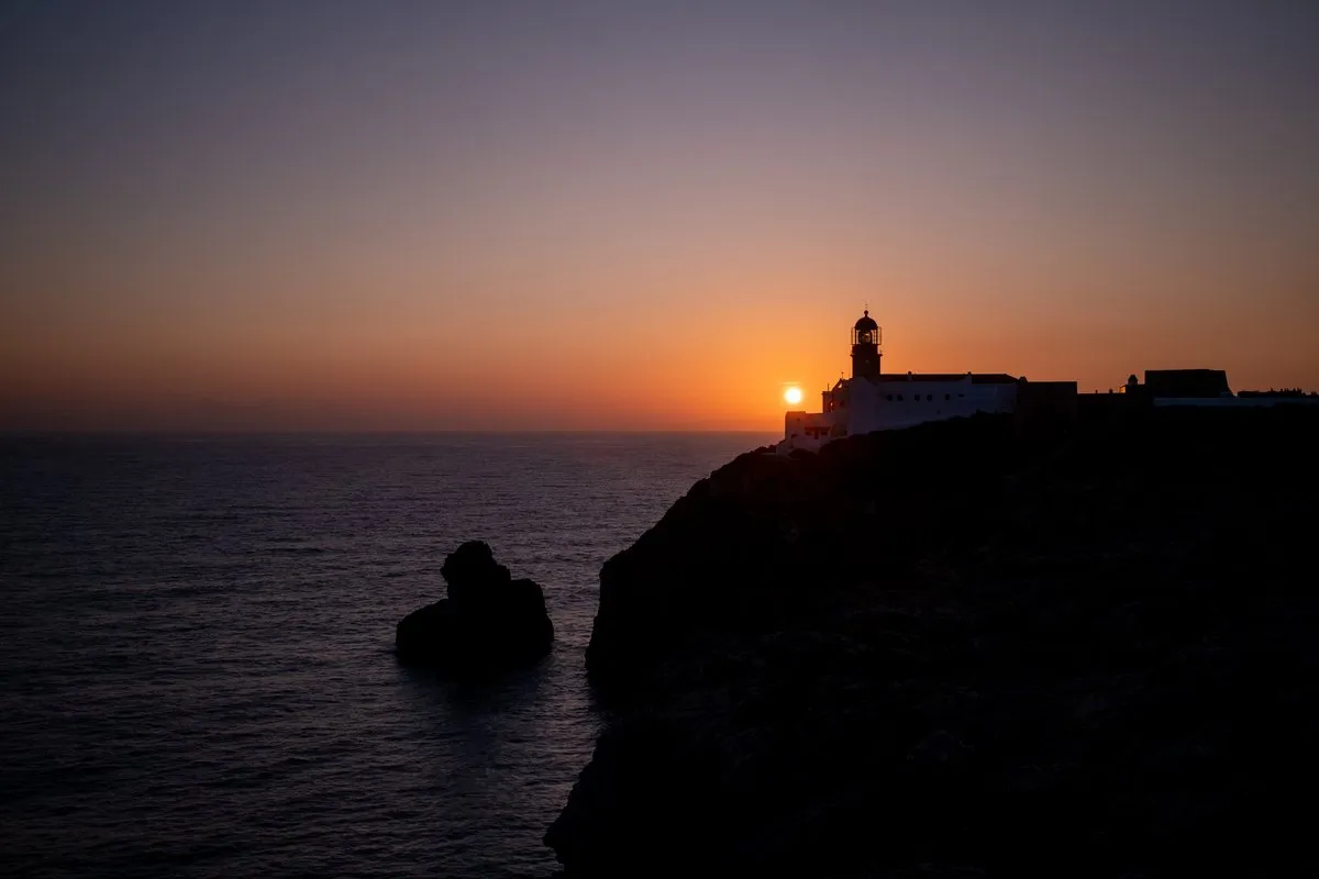 Leuchtturm auf einer Klippe bei Sonnenuntergang über dem Meer